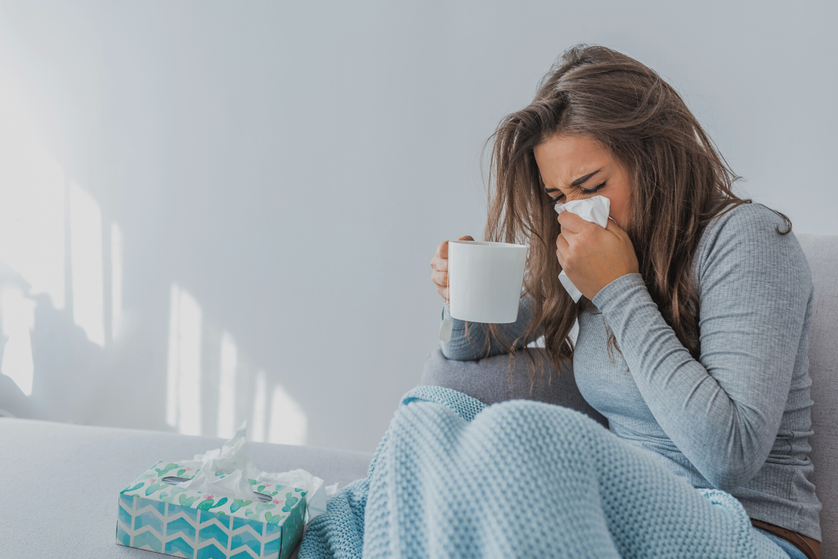 Sjuk kvinna som snyter sig i en näsduk