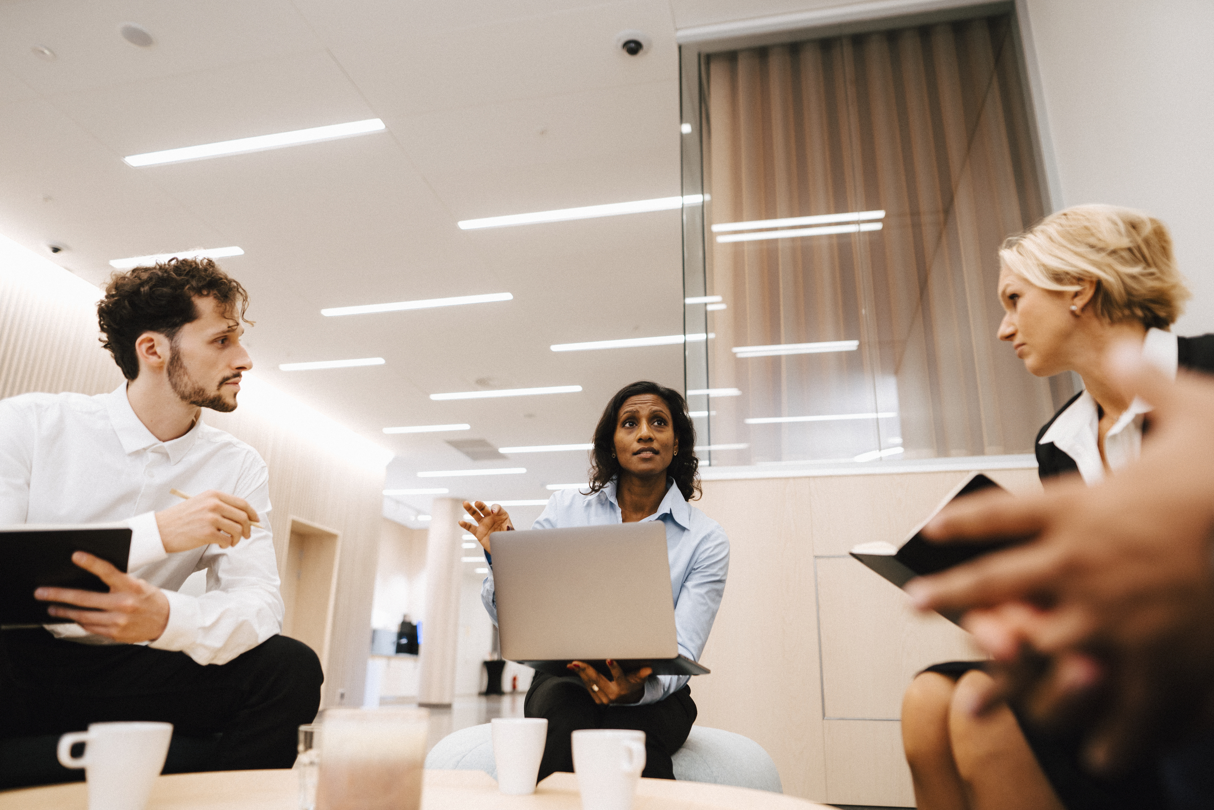 Tre personer sitter i ett möte och diskuterar.